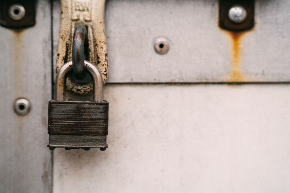 Close-up of a rusty metal padlock on a weathered door, highlighting security and decay.