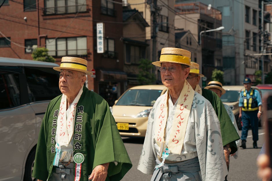 Elderly men in traditional attire participate in a cultural parade during a sunny day in Tokyo.