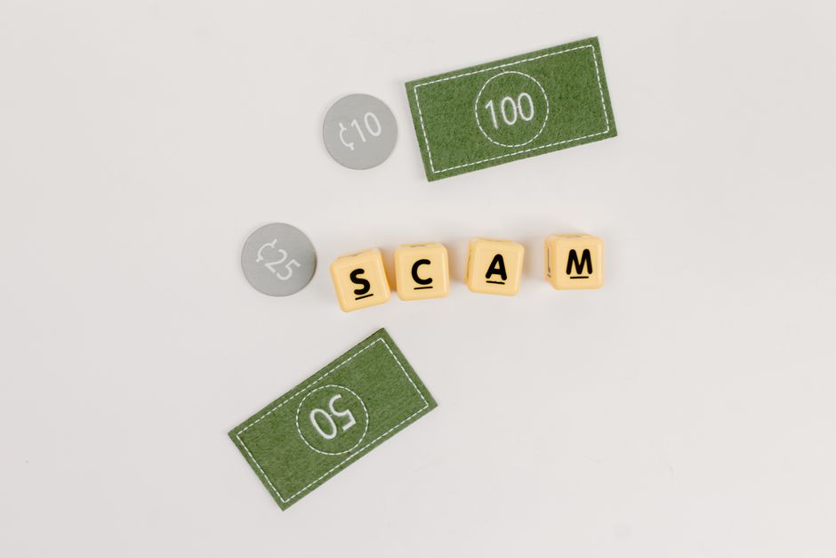 Flat lay of fake currency and scam letters on a gray surface representing financial deception.