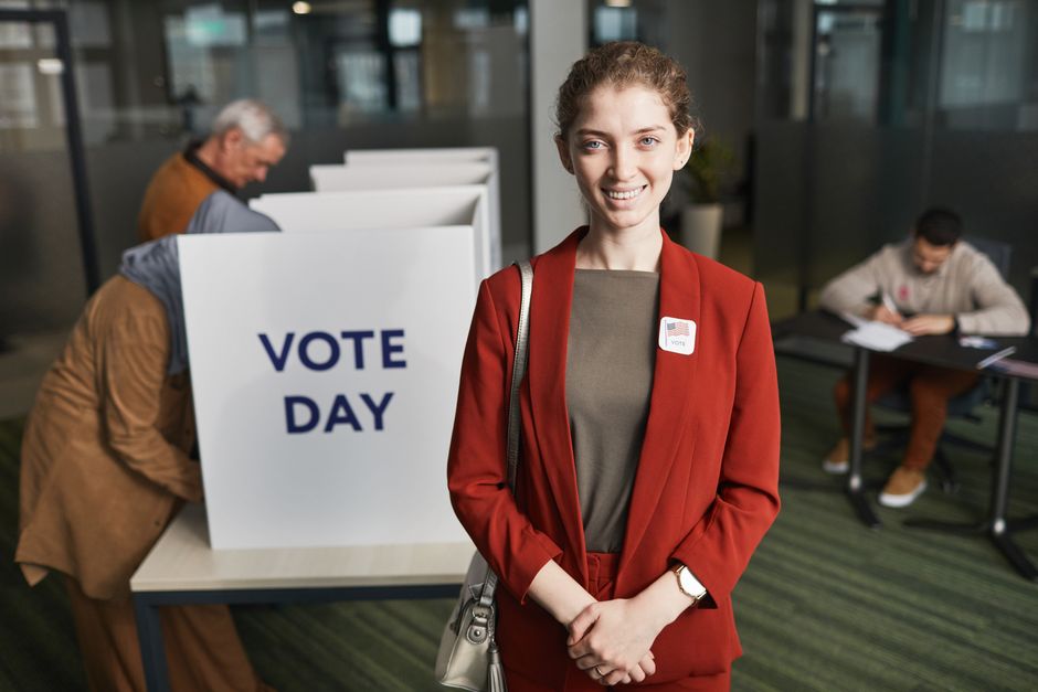 Woman in red suit at voting station, promoting civic engagement on election day.