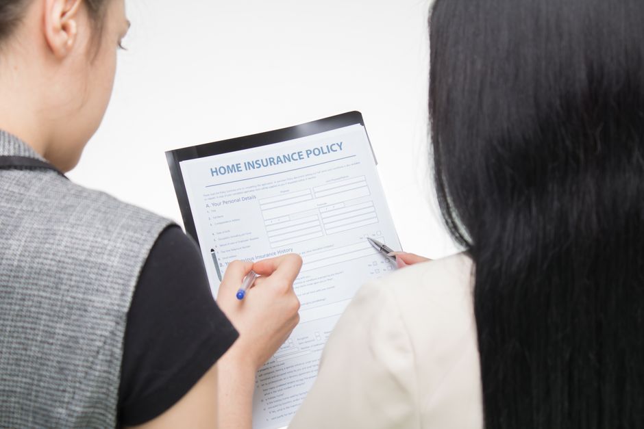 A person at a kitchen table reading through a printed insurance policy document
