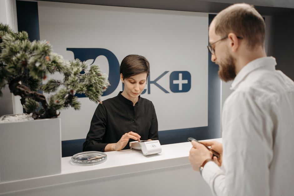 A pet owner paying at a veterinary clinic front desk with a card reader