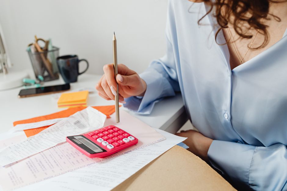 A person using a calculator while sorting through a stack of paper bills
