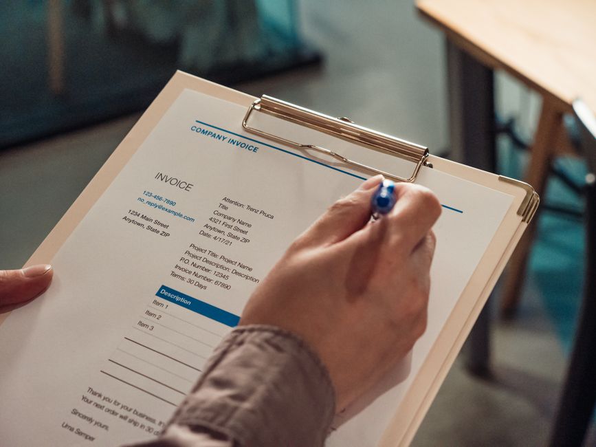 A printed itemized invoice lying on a desk next to a pen and calculator
