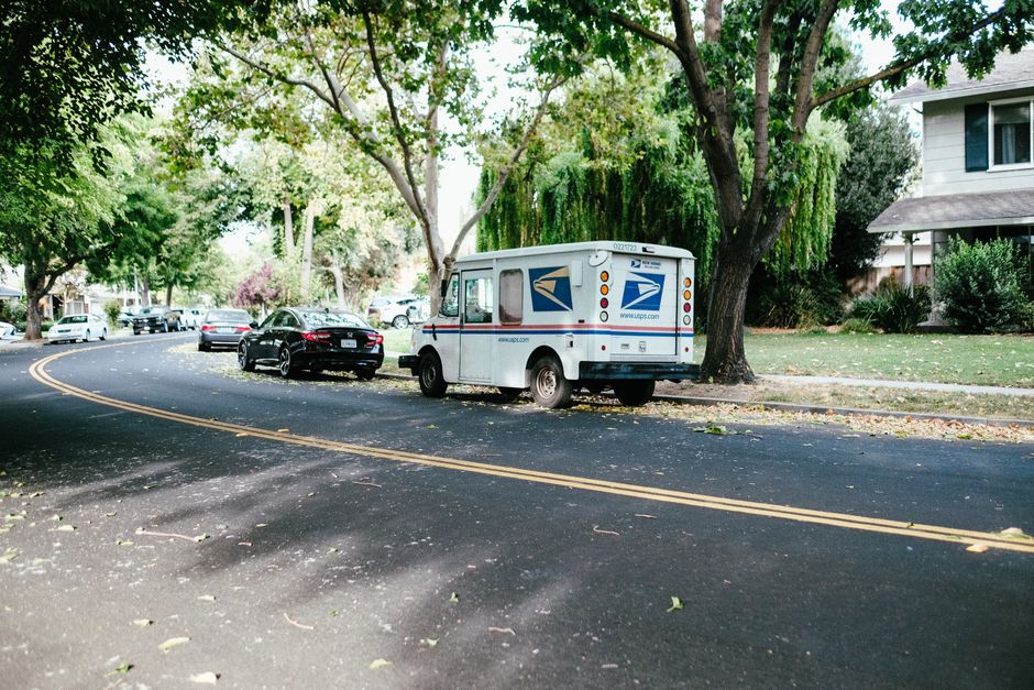 A delivery van driving along a quiet residential street lined with houses