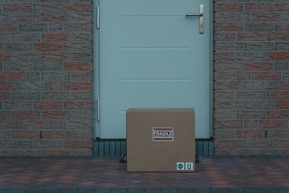 A cardboard shipping box left on the front doorstep of a house