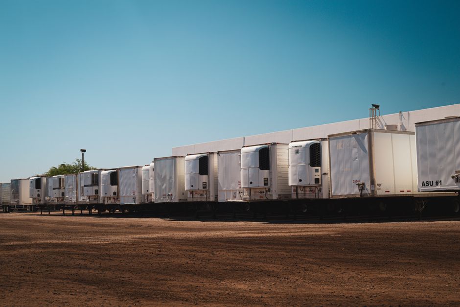 Several parcel delivery trucks parked in a row outside a distribution facility