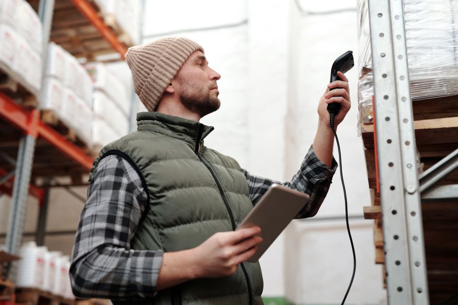 Warehouse worker holding a handheld scanner over a barcode label on a cardboard box