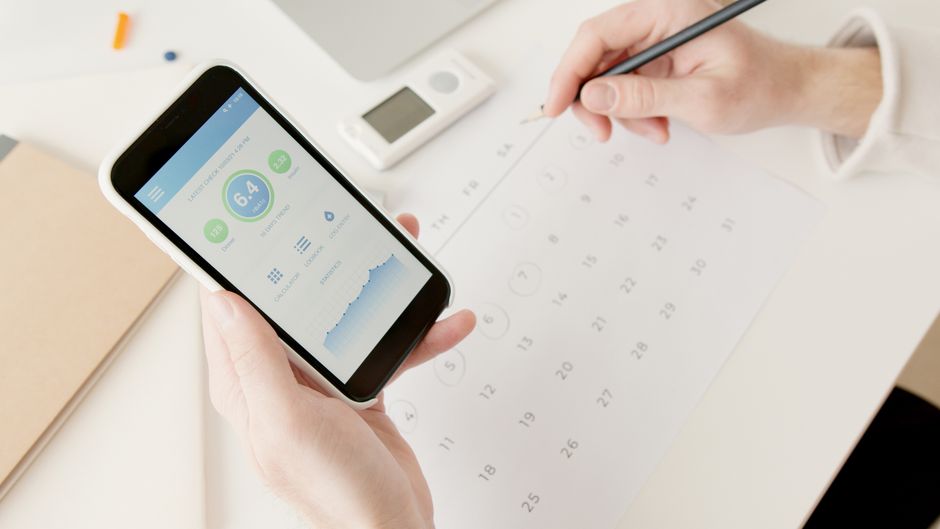 A person standing indoors looking at a package tracking screen on a smartphone
