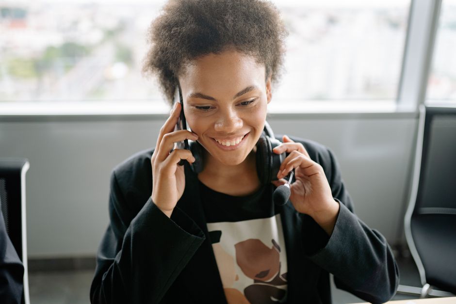 A person seated at a desk making a phone call while holding a shipping receipt