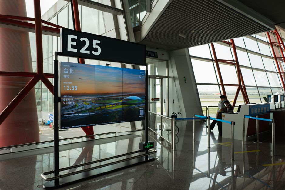 Agent speaking into a microphone at an airport gate counter near a crowd