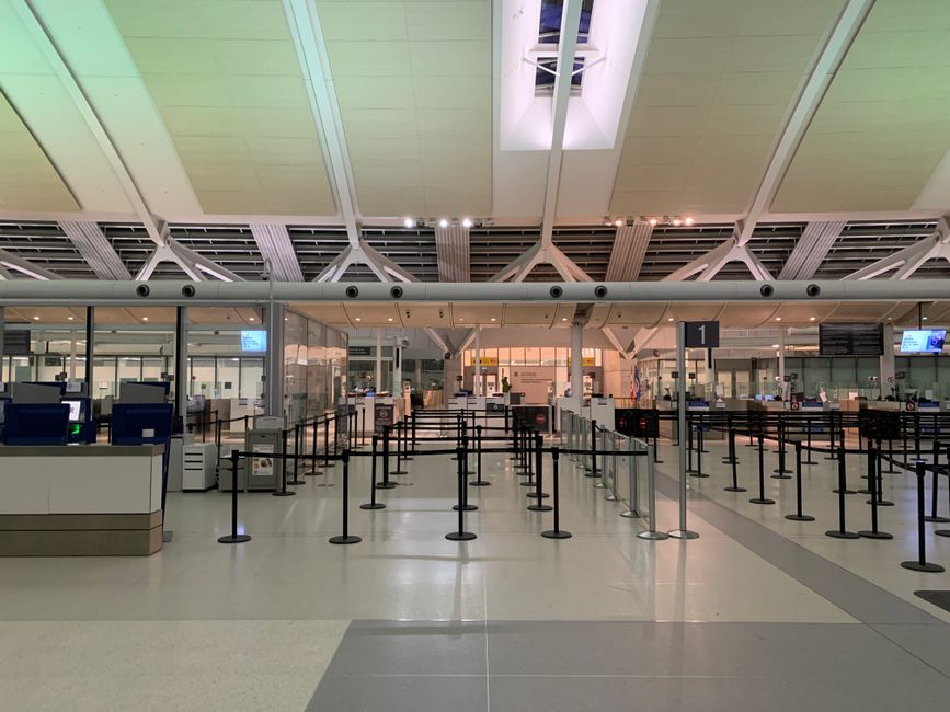 Airline gate agent standing at a boarding desk speaking with waiting passengers