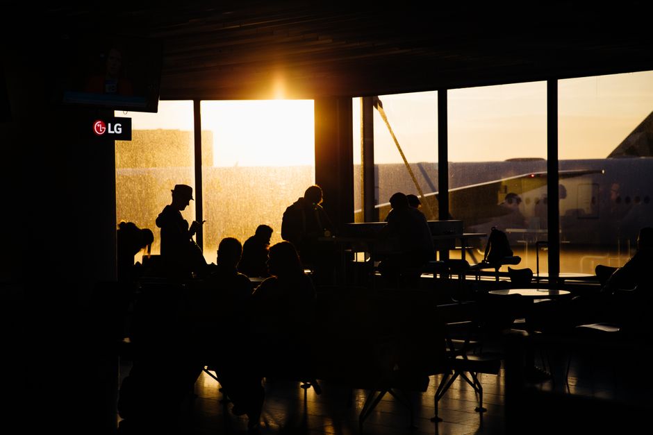 Travelers seated in an airport departure lounge watching the gate podium