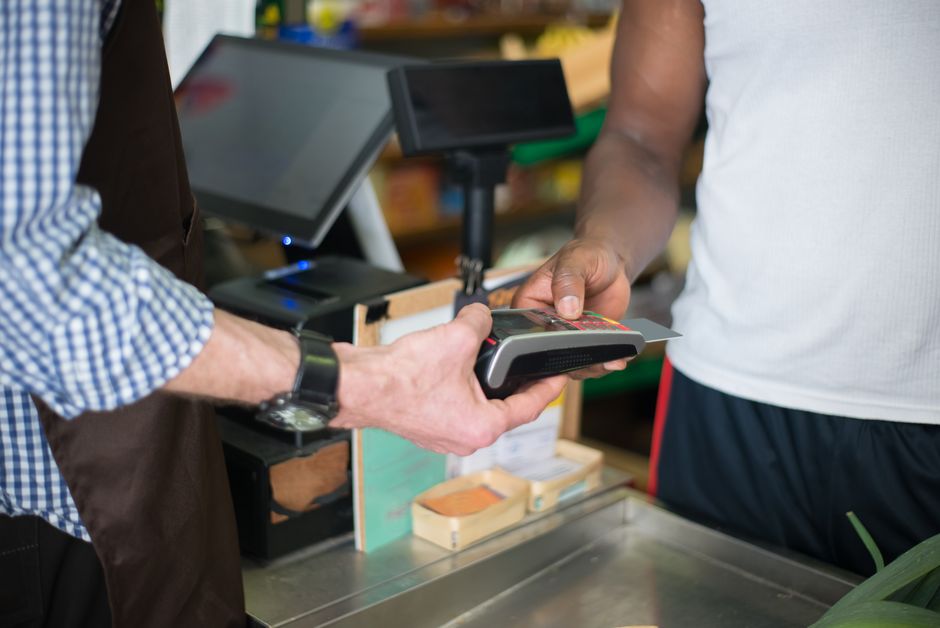 A shopper handing a card to a cashier at a retail store counter