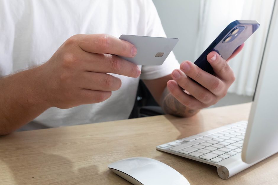 A person checking a banking app on a smartphone while holding a card