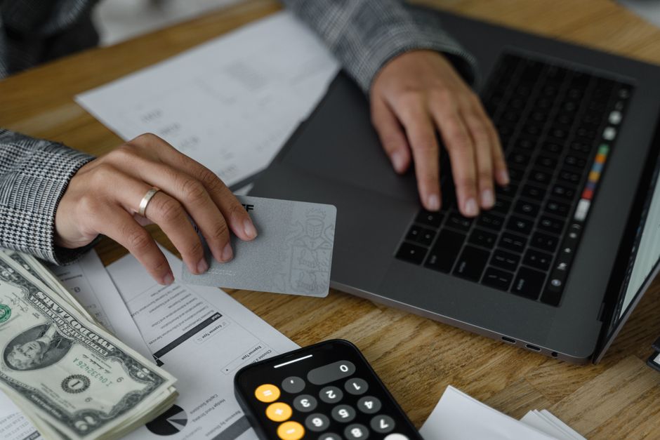 A credit card statement on a desk beside a calculator and pen