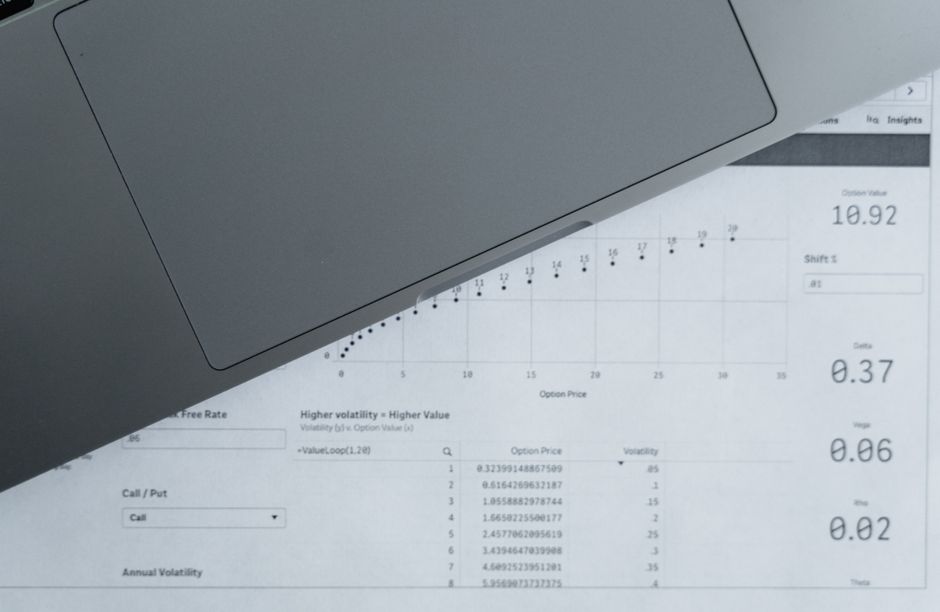 A laptop screen showing a spreadsheet of numbers next to a notepad