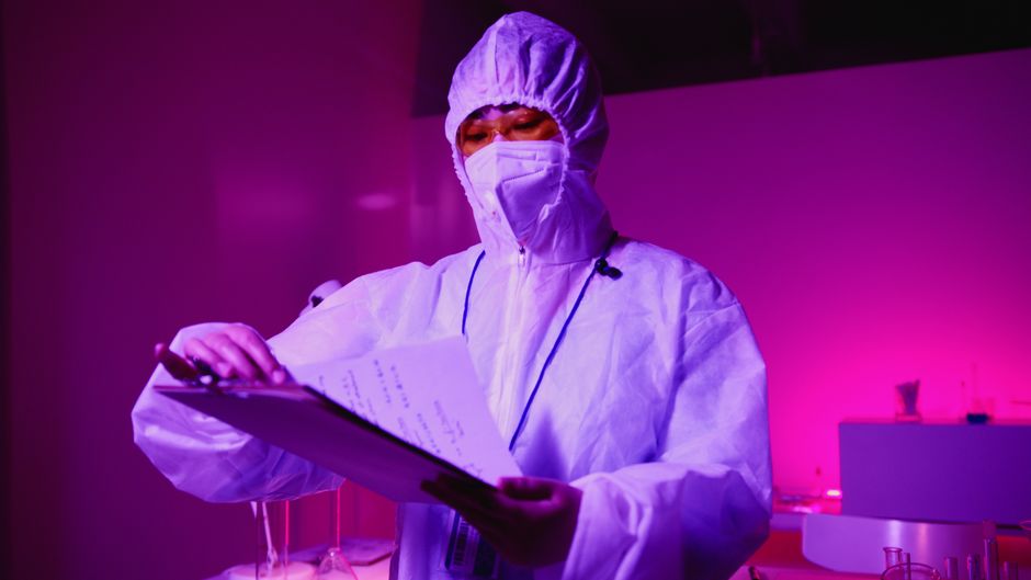 A scientist in a lab coat reading printed data sheets at a desk