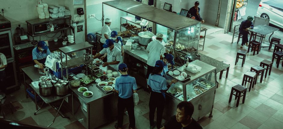 A health inspector with a clipboard checking a stainless steel commercial kitchen
