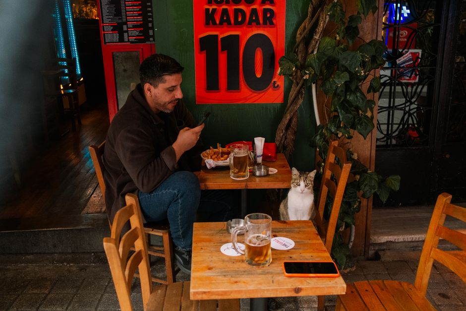 A person standing outside a restaurant looking something up on a smartphone