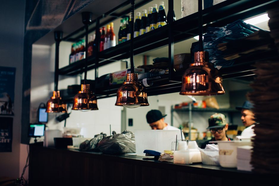 Line cooks working at a busy restaurant kitchen pass during dinner service