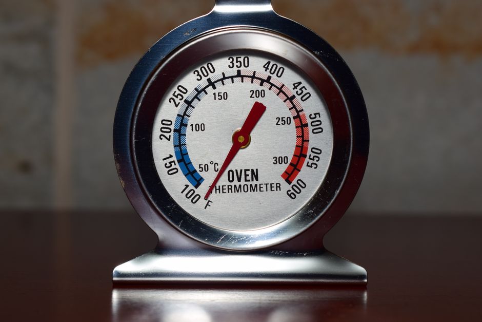 An inspector inserting a probe thermometer into food to check its holding temperature
