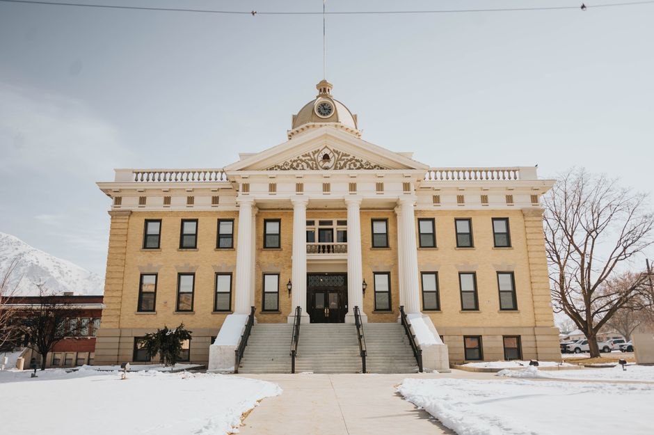 Stone county courthouse building with columns and steps seen from the sidewalk