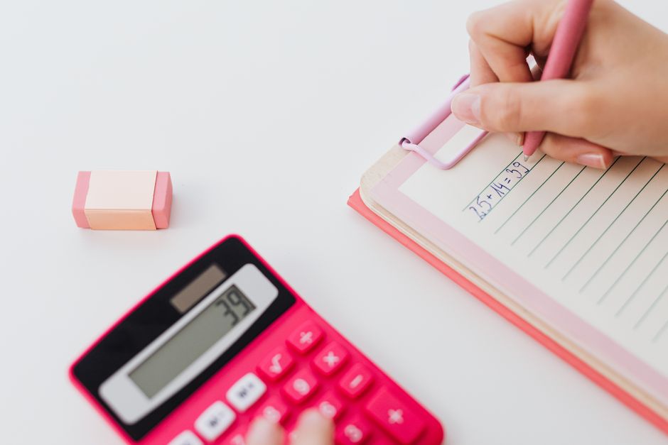 A musician at a desk working through figures on a calculator beside a notebook