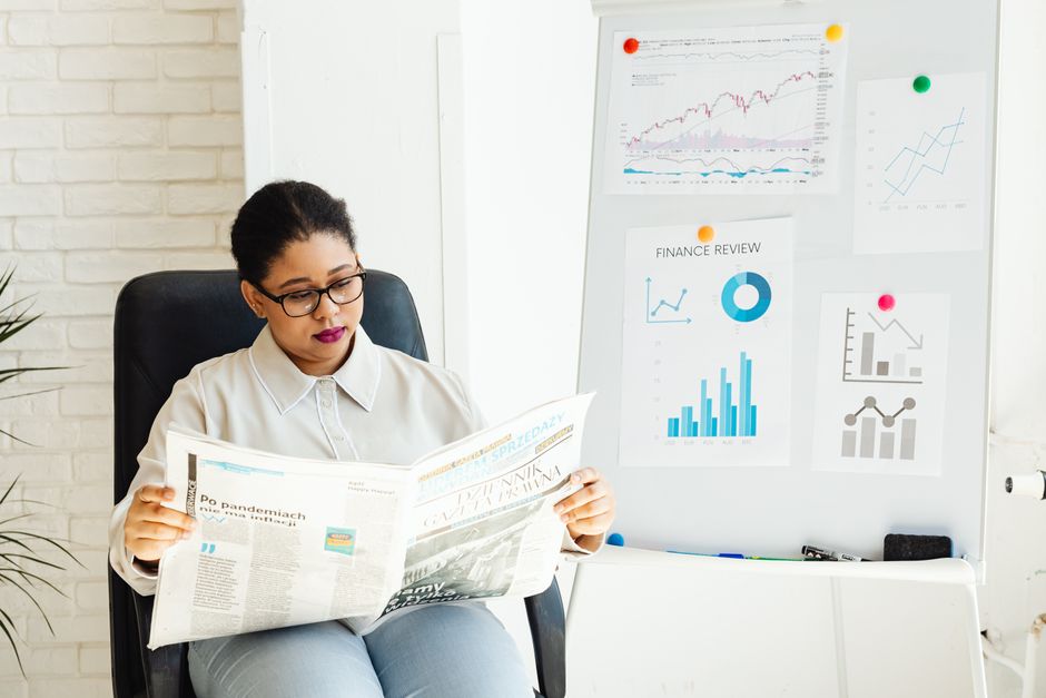 A person reading printed financial charts and figures spread across a table