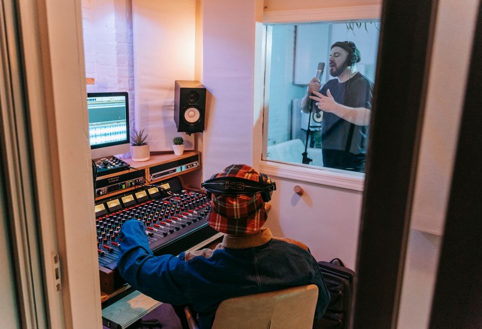 A musician working at a mixing desk in a small recording studio