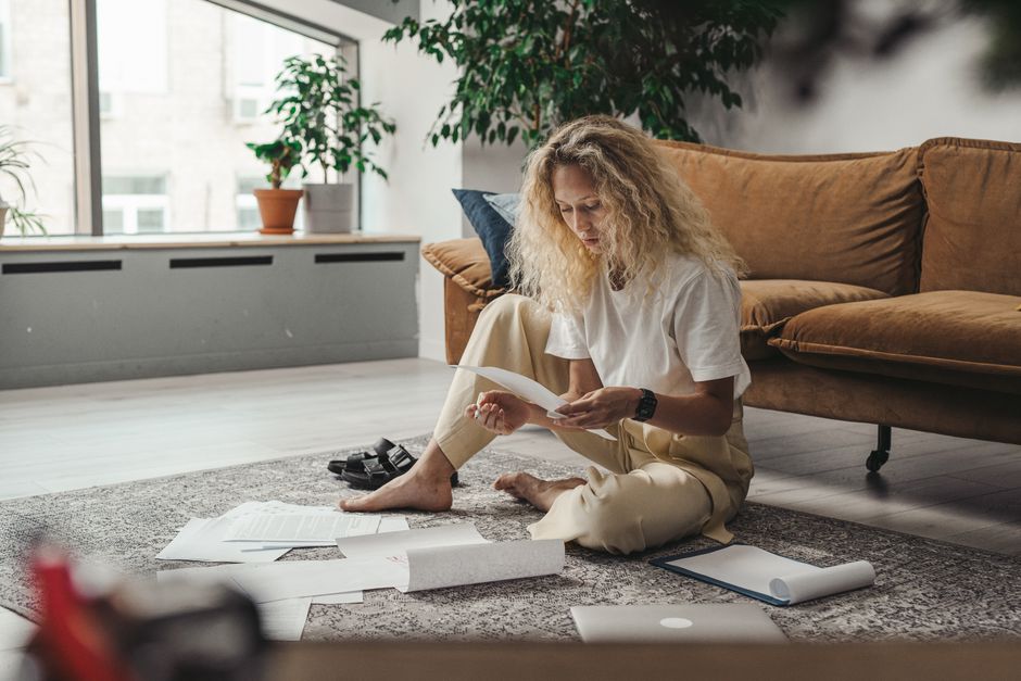 A guitarist sitting with an acoustic guitar while reading a printed statement
