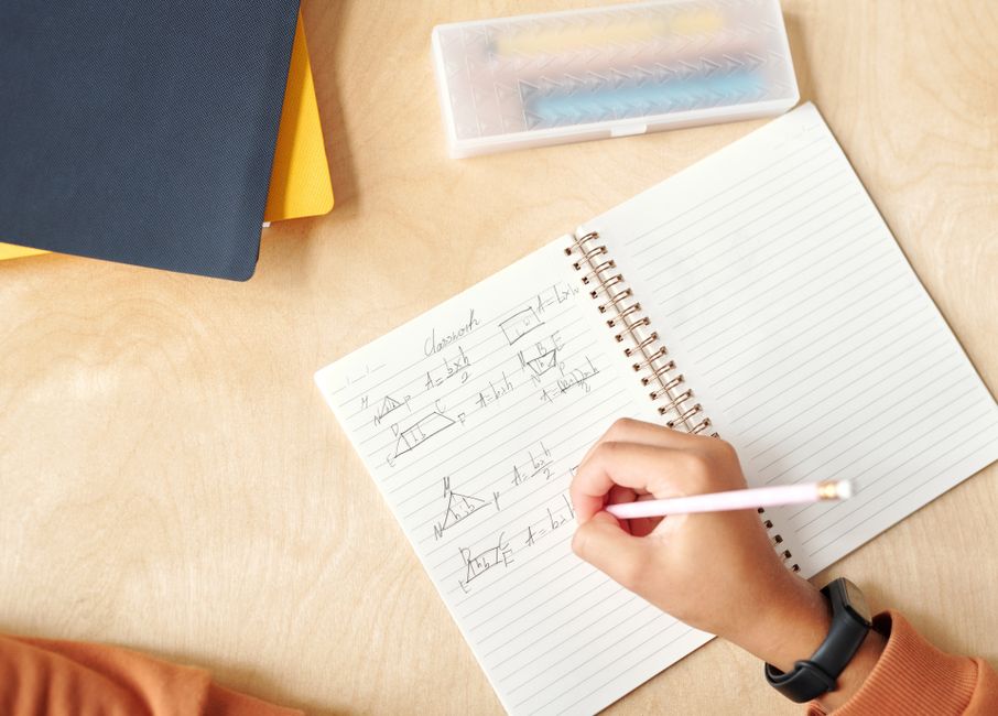 Handwritten arithmetic and division worked out in pencil on lined notebook paper