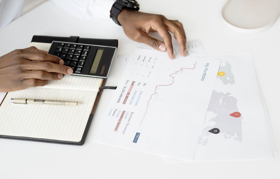 Calculator resting on printed financial spreadsheets covered in numbers
