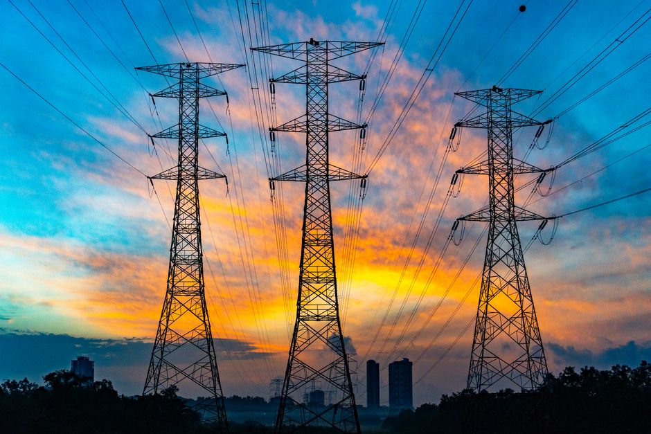 High voltage transmission towers and power lines silhouetted against an evening sky