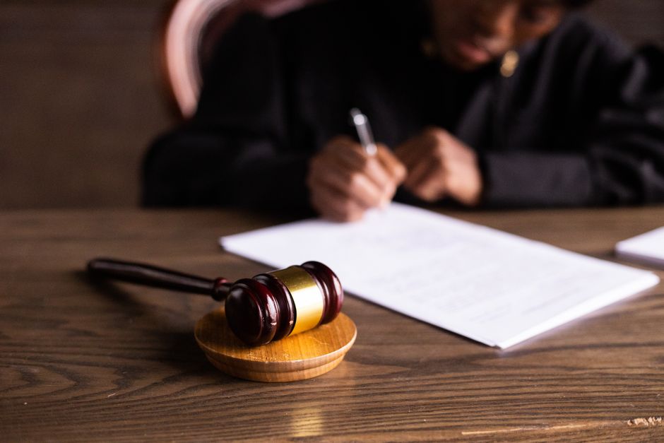 A wooden gavel resting on a bench in an empty courtroom