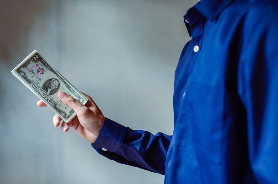 A person at a table examining a paycheck and household bills