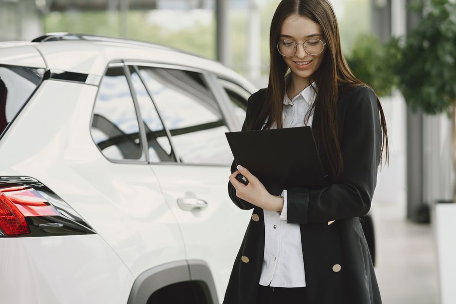 A customer signing paperwork across a desk from a salesperson at a car dealership