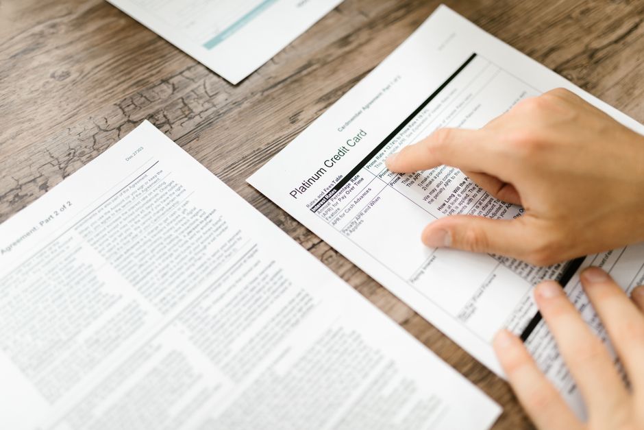 Close-up of hands holding a printed contract, reading the fine print on the page
