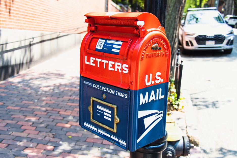 A certified mail envelope being removed from a residential curbside mailbox