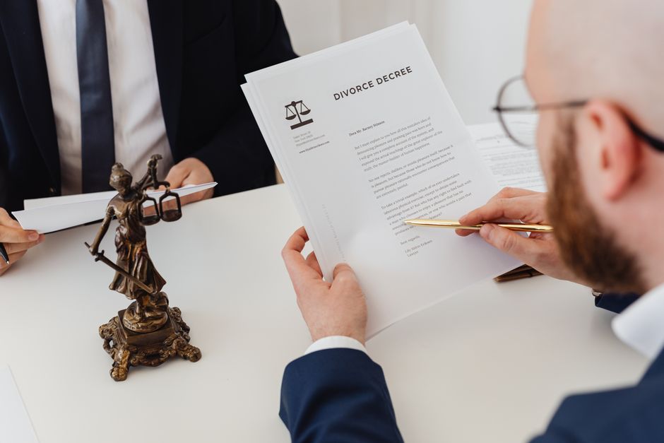 A person at a kitchen table reading a thick stack of printed legal documents
