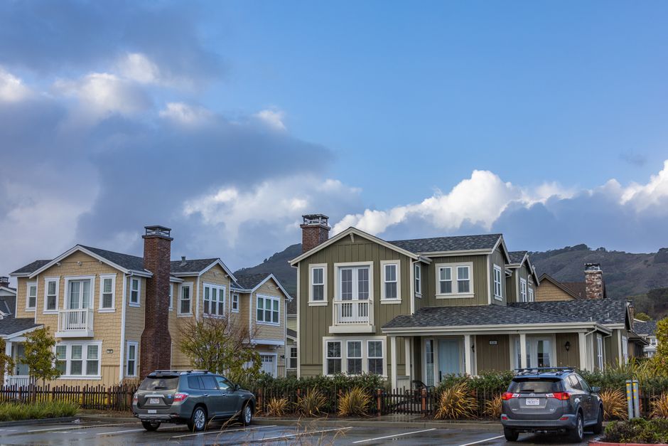 Row of similar suburban houses with uniform lawns and matching exterior paint colors