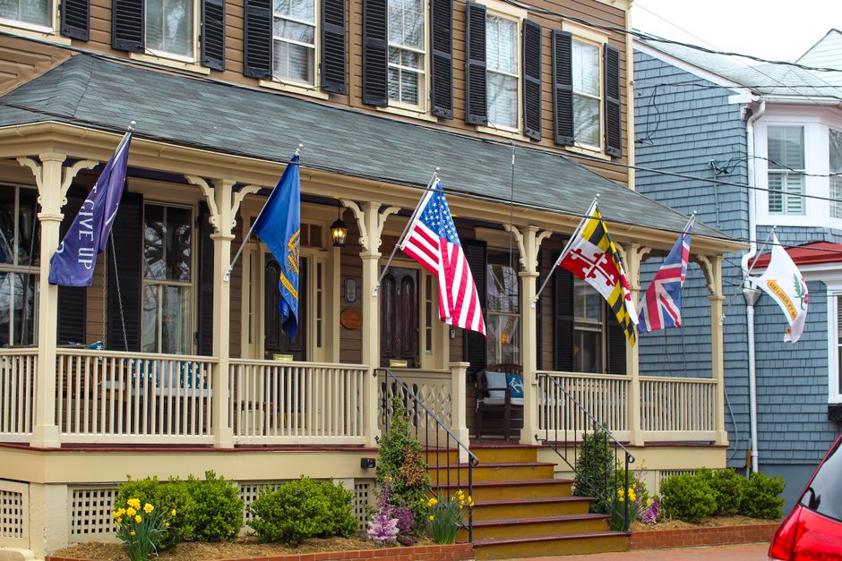 An American flag mounted on a bracket beside the front porch of a home