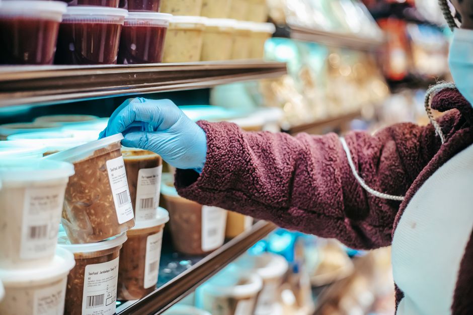 Person in a kitchen holding a food package and reading the label closely
