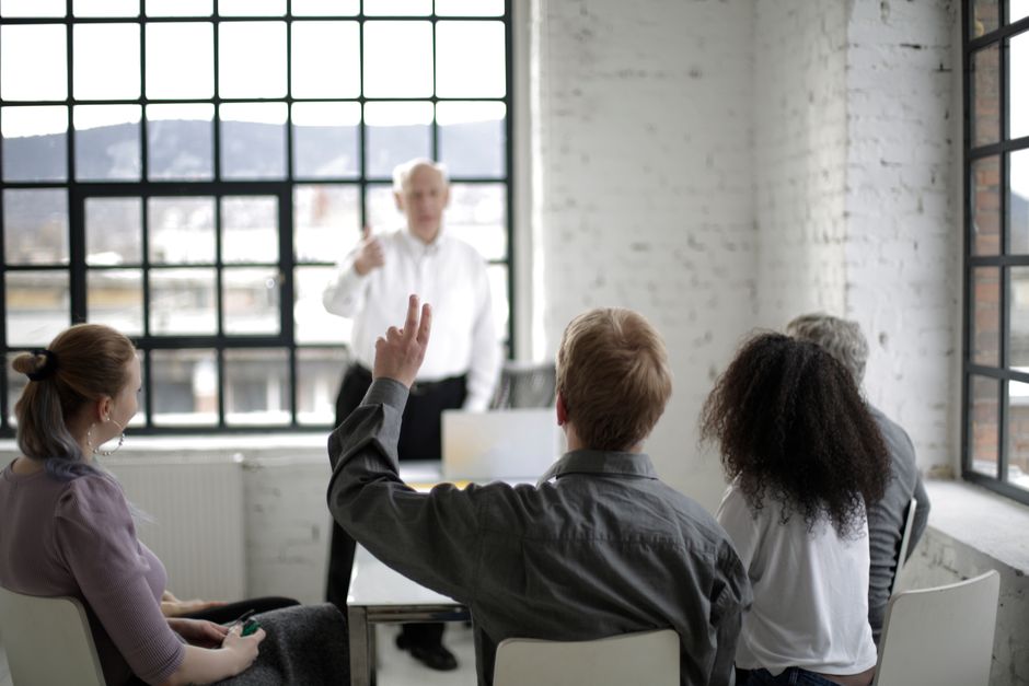 An employee asking a question during a small workplace benefits meeting