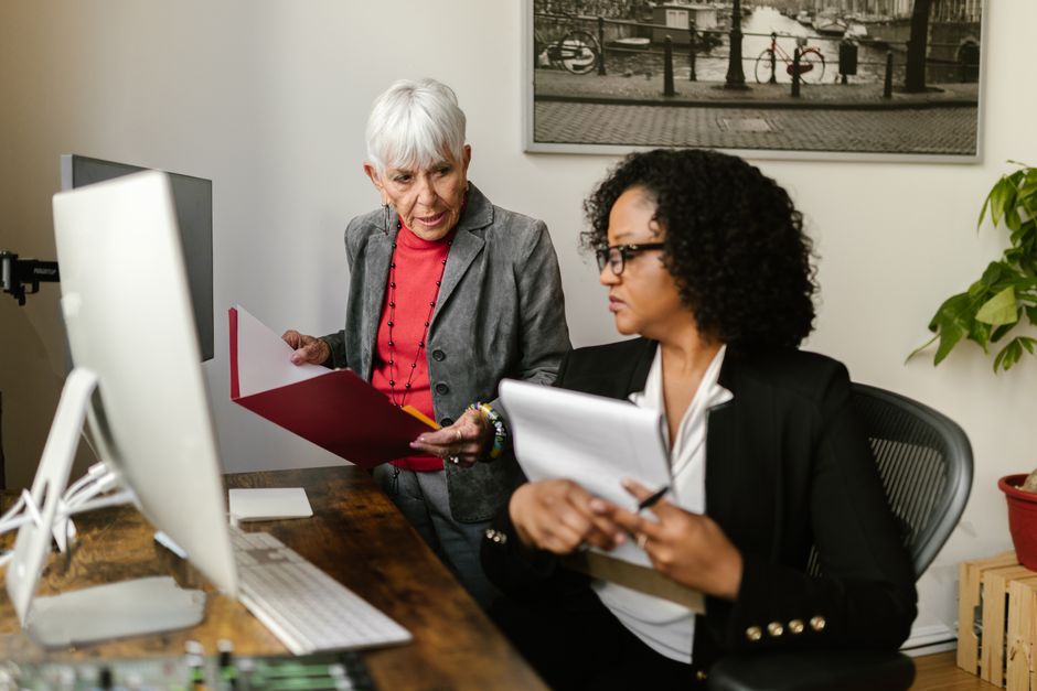 Two people reviewing printed plan documents across an office desk