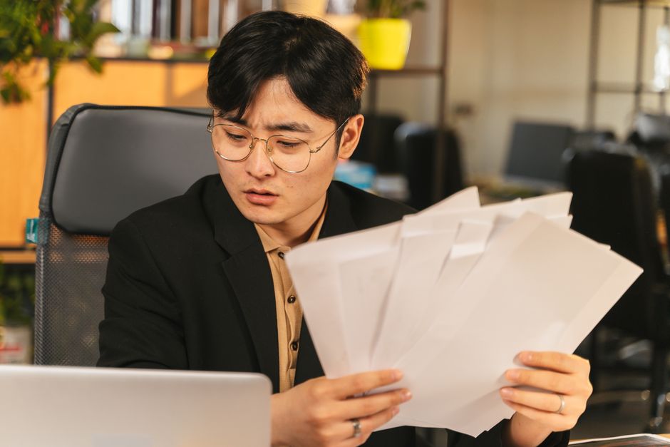 A person at a desk reading a stack of employee benefits documents
