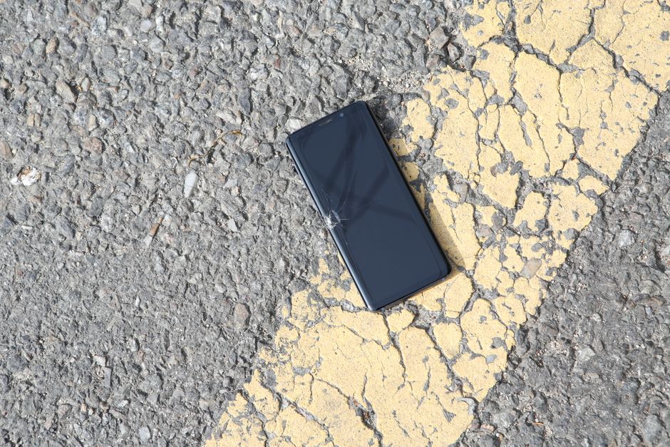 Person on a phone inside a house looking at water-damaged ceiling and wall