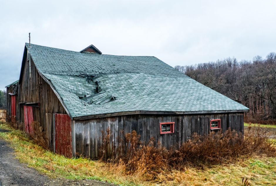 Close-up of storm-damaged asphalt shingles with missing and cracked pieces