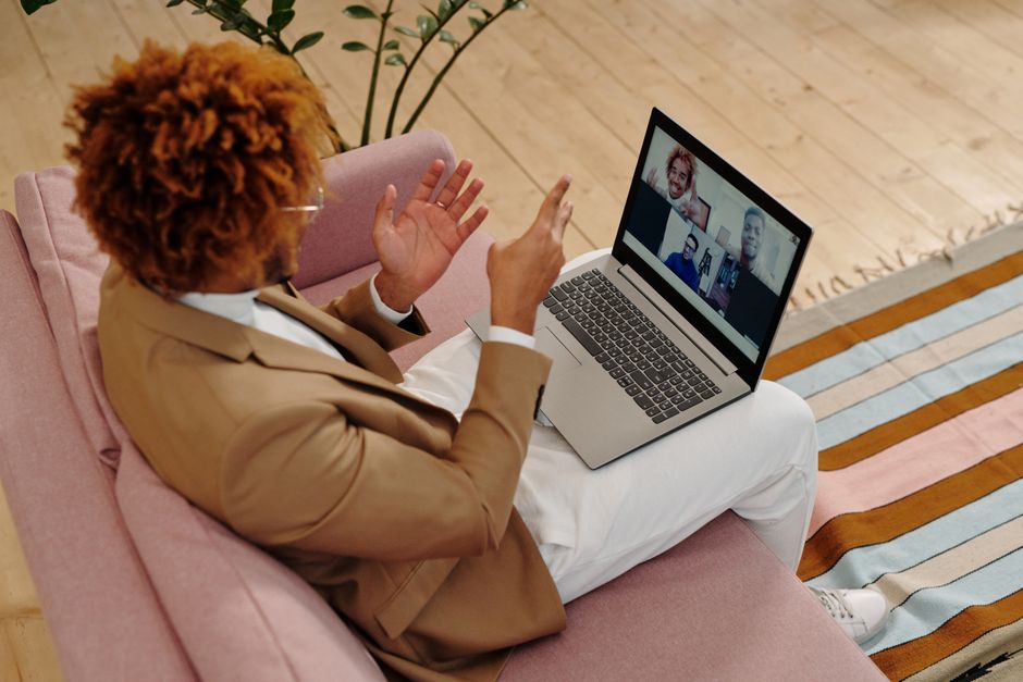 Person on a laptop video call taking notes during a professional meeting