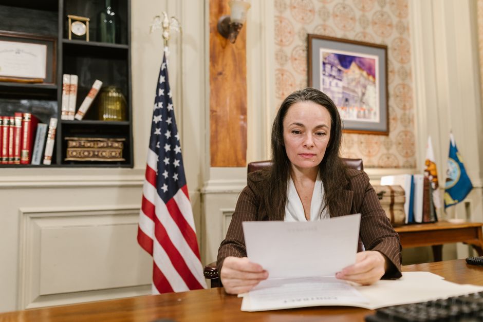 Person at a table reading an official letter with a serious expression